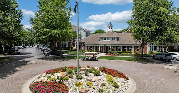 a flag pole in the middle of a flower garden in front of a house