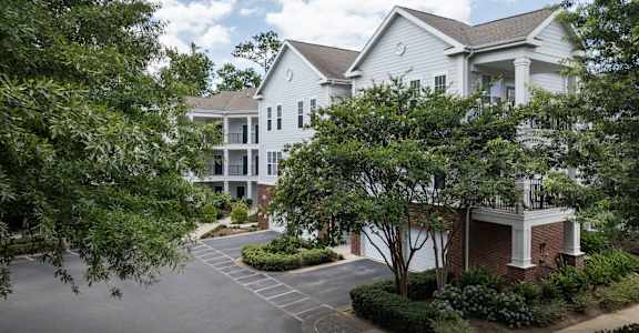 the view of an apartment building with a driveway and trees