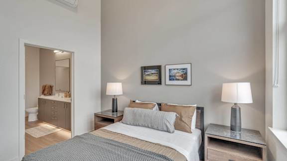 a bedroom with a bed and two lamps and a bathroom