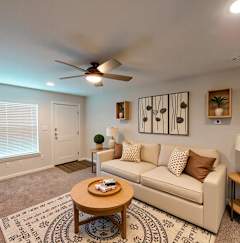 A living room with a beige couch, a coffee table, and a ceiling fan.