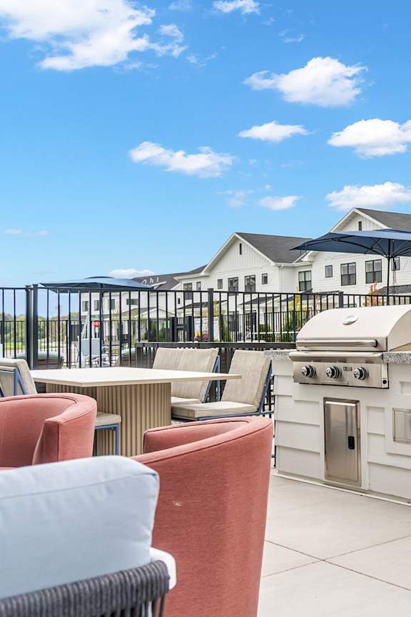 A patio with a table, chairs, and a grill. at Sandhill Parkway Townhomes Apartments, East Bethel, Minnesota