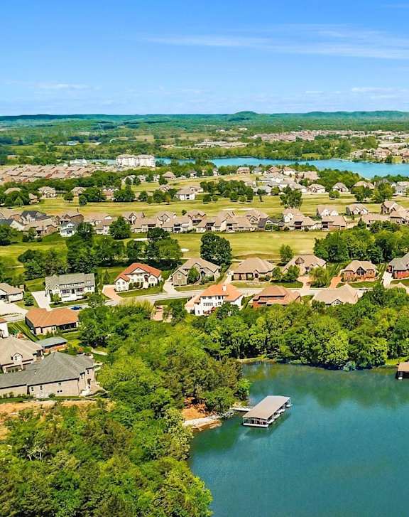 A bird's eye view of a residential area with houses surrounding a body of water.