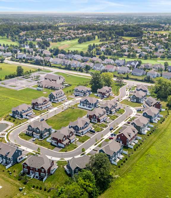 A bird's eye view of a residential neighborhood with houses and a pond.