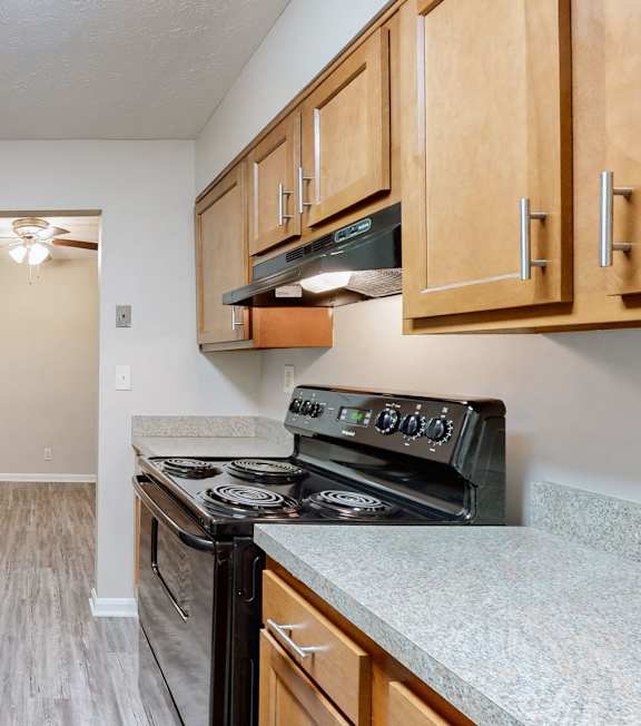 an empty kitchen with wood cabinets and black appliances
