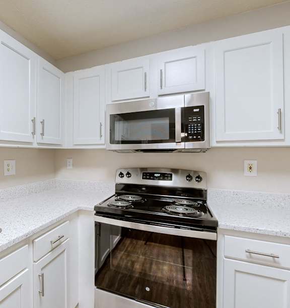 A kitchen with white cabinets and a stove top oven.