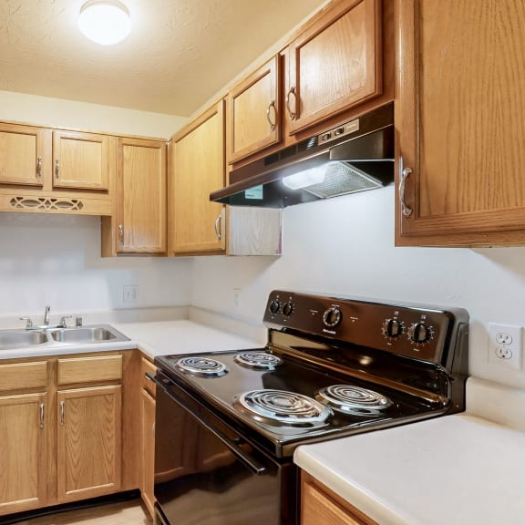 a kitchen with wood cabinets and black appliances and white counter tops