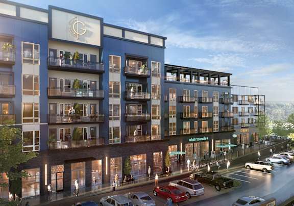 A modern apartment building with a parking lot in front.