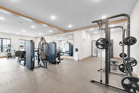 A gym with a variety of equipment including a treadmill, weights, and a bench press. at Sandhill Parkway Townhomes Apartments, East Bethel, Minnesota