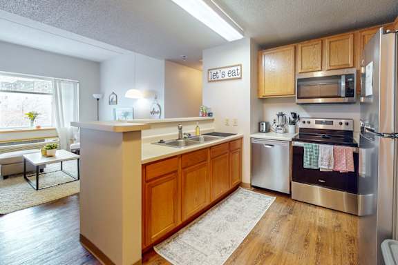 a kitchen with stainless steel appliances and wooden cabinets, at Bierman Place, Minneapolis