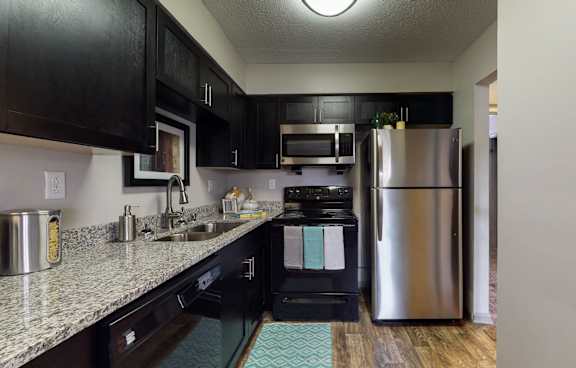 A kitchen with black cabinets and a stainless steel refrigerator.