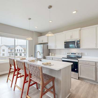 A kitchen with white cabinets and a large island with a sink.