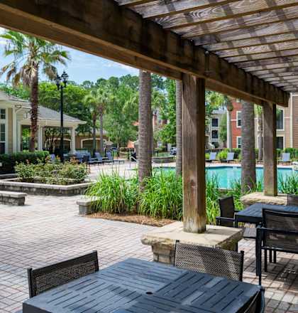 A patio with a table and chairs under a wooden pergola.