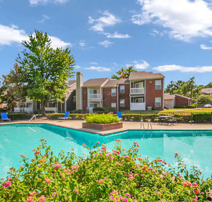 A swimming pool surrounded by flowers and residential buildings.