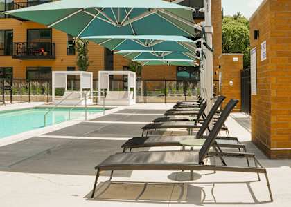 A pool area with sun loungers and umbrellas.