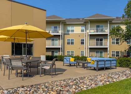 an outdoor patio with tables and umbrellas at chaska place apartments