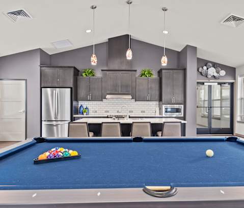 A pool table with a white ball and a set of 15 balls is in the middle of the room.