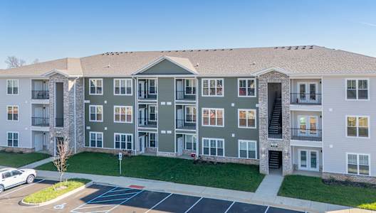 A large apartment complex with a parking lot in front.