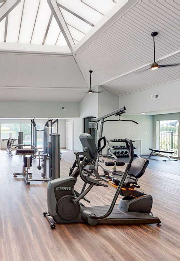 a gym with cardio machines and a flat screen tv