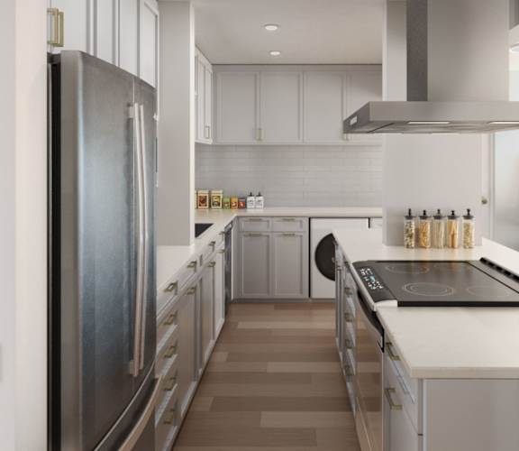 A modern kitchen with a refrigerator on the left and a stove top oven on the right at Ocean Edge @ Laguna Beach Apartments, California