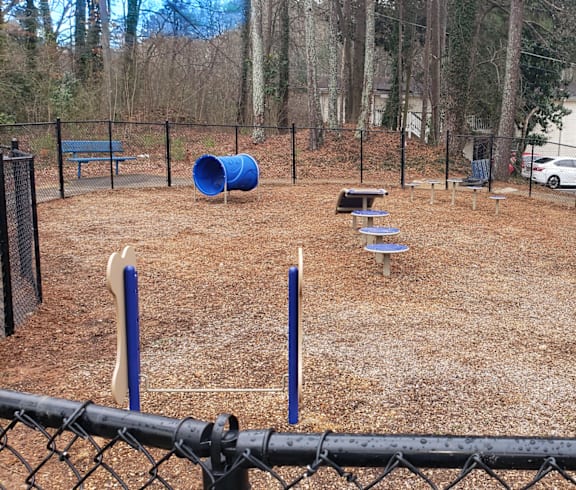 A playground with a blue barrel, a slide, and a bench.