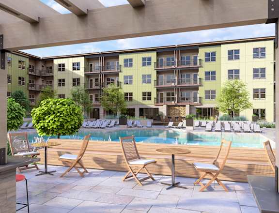 a pool with chairs and tables in front of an apartment building at Boardwalk at Research Park, Alabama, 35811