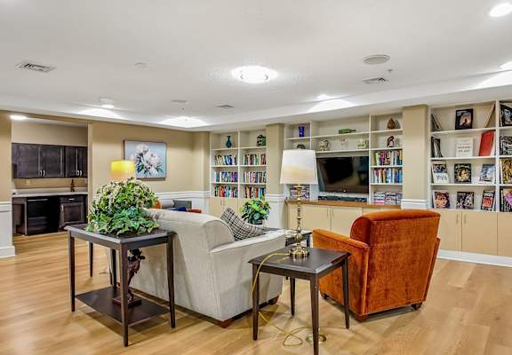 A living room with a fireplace, a couch, a chair, and a bookshelf filled with books.