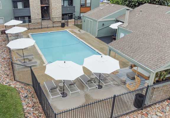 an aerial view of a resort style pool with umbrellas and lounge chairs