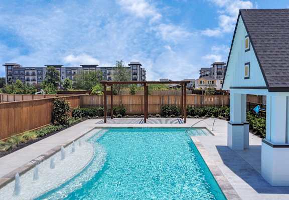 a pool in a backyard of a home with a fence and apartment buildings in the background