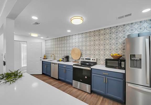 A modern kitchen with stainless steel appliances and blue cabinets. at The Stella Apartments, Memphis, TN