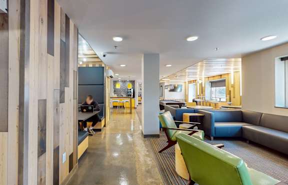 a lobby with blue couches and green chairs and a table, Student Housing in Minneapolis