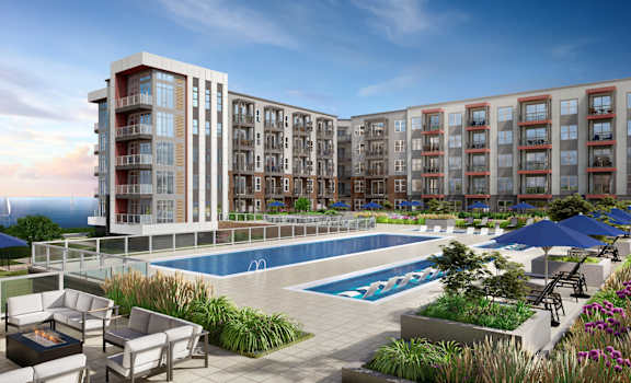 A modern apartment complex with a pool and outdoor seating area.
