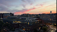 A cityscape at dusk with buildings and a street intersection.