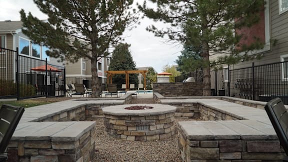 a fire pit and seating area at the whispering winds apartments in pearland, tx