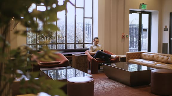 A man is sitting on a chair in a room with a large window.