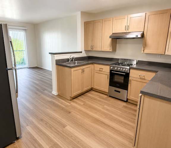 A kitchen with wooden cabinets and a black refrigerator.