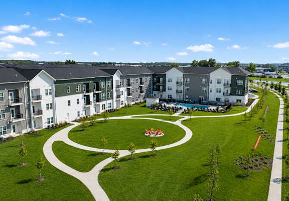 A large grassy area with a playground in the middle of apartment buildings.