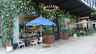 A blue umbrella is in front of a store with a sign that says "coffee".