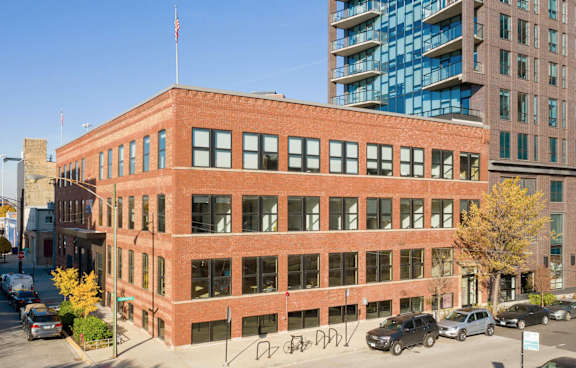 A red brick building with a flag on top is in the middle of a street.