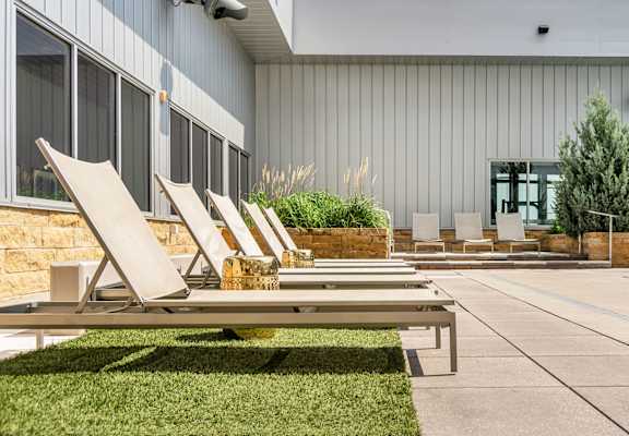 A poolside area with lounge chairs and a building in the background. at Custom House, Saint Paul, Minnesota