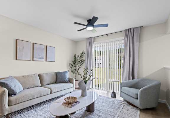 A living room with a grey couch, a coffee table, and a ceiling fan.