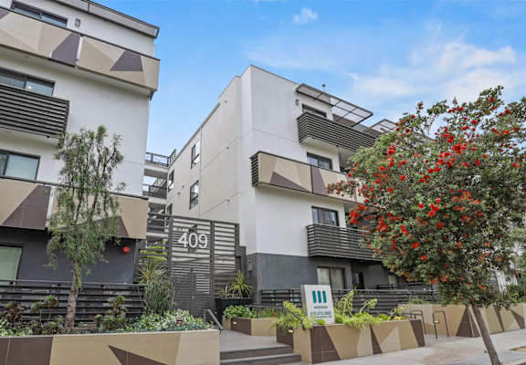 a group of apartments with a sidewalk and trees in front of them