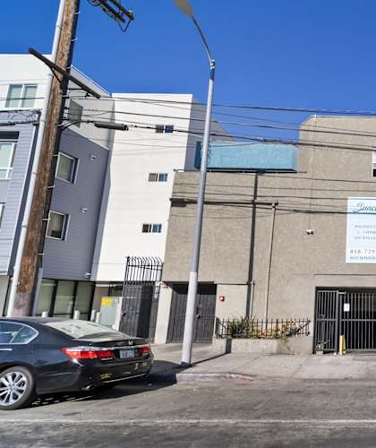 A car is parked in front of a building with a blue awning.