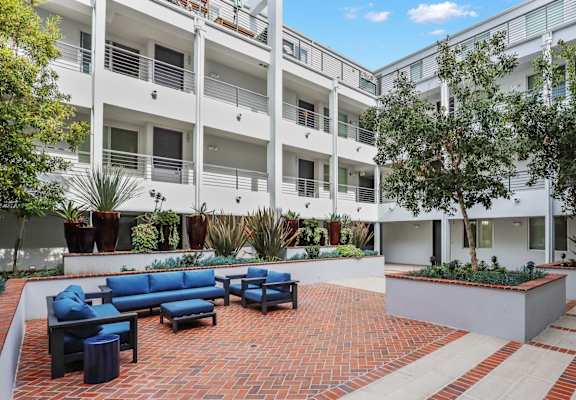 an outdoor area with couches and chairs in front of an apartment building