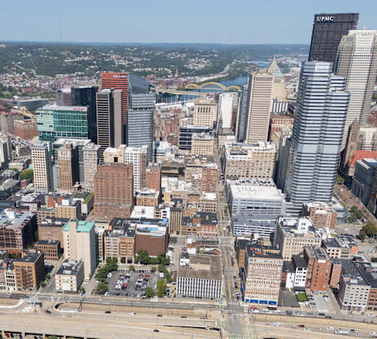 A cityscape with a mix of modern and older buildings, a highway, and a body of water in the distance. at The Commonwealth Building, Pittsburgh, 15222