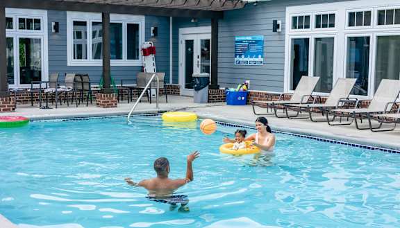 A man is swimming in a pool with a child and a ball. at Highland Village, Pennsylvania