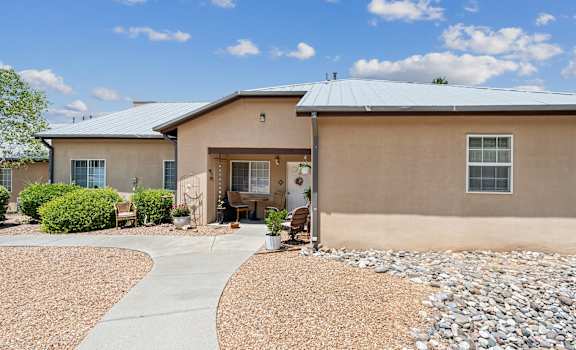 a beige house with a gravel yard and a sidewalk