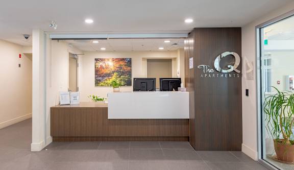 a reception area with a white reception desk and a glass door