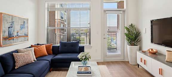 A living room with a blue couch and a painting on the wall.