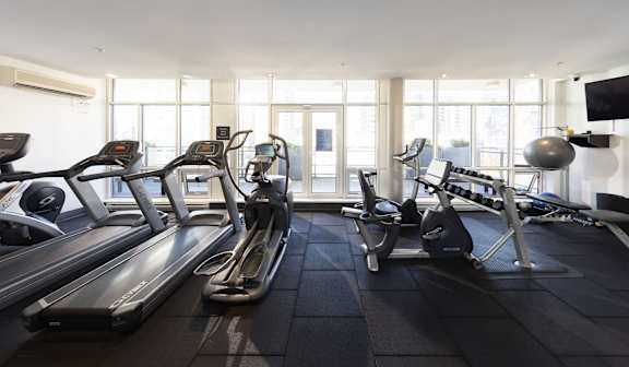a gym with cardio equipment and windows in a hotel room