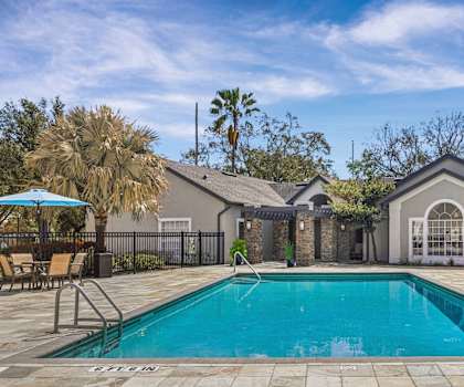 A pool surrounded by a patio and a house.